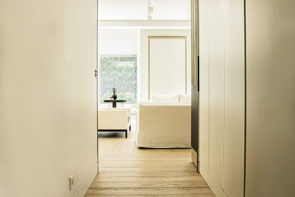 Minimalist hallway with custom cabinetry leading to a bright bedroom in Neuilly near Paris.