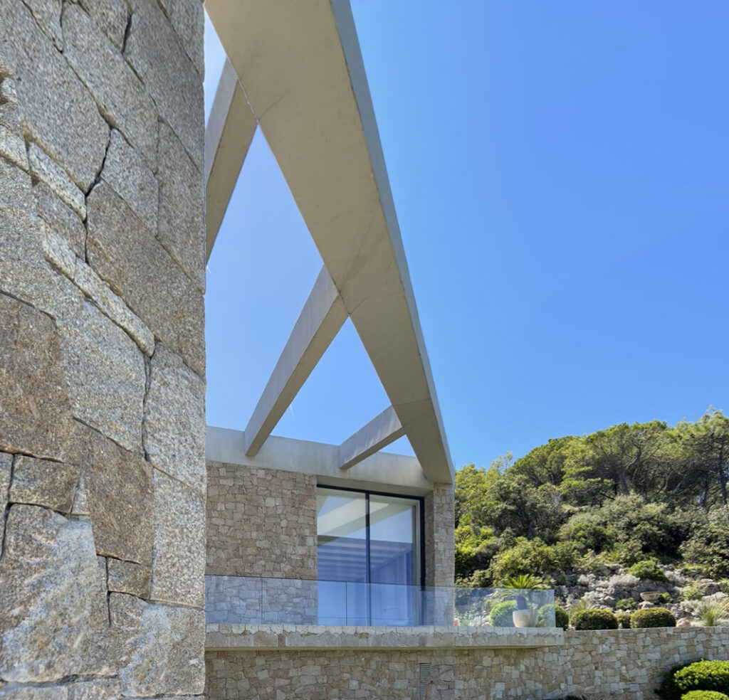 A dialogue between raw mineral textures and precise structural lines, framing light, sky, and vegetation.