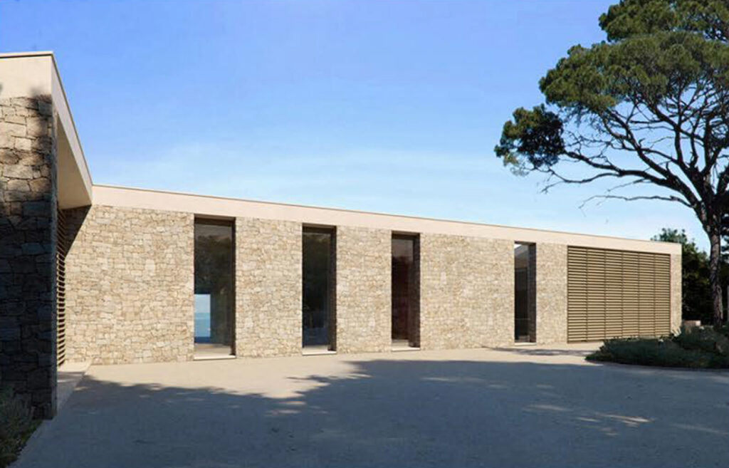 A restrained, monolithic façade crafted in natural stone, echoing the strength of a coastal fortress while blending seamlessly into the Mediterranean landscape.