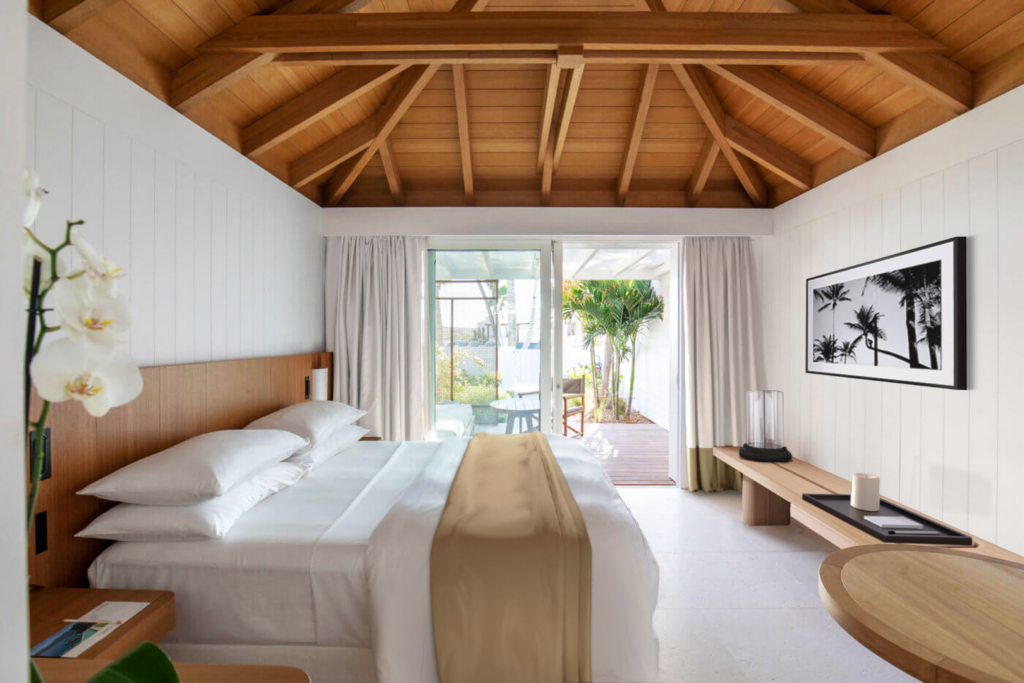 Interior view of a guest suite at Le Sereno Hotel in St. Barthélemy with exposed wooden ceiling, custom furnishings and terrace opening.