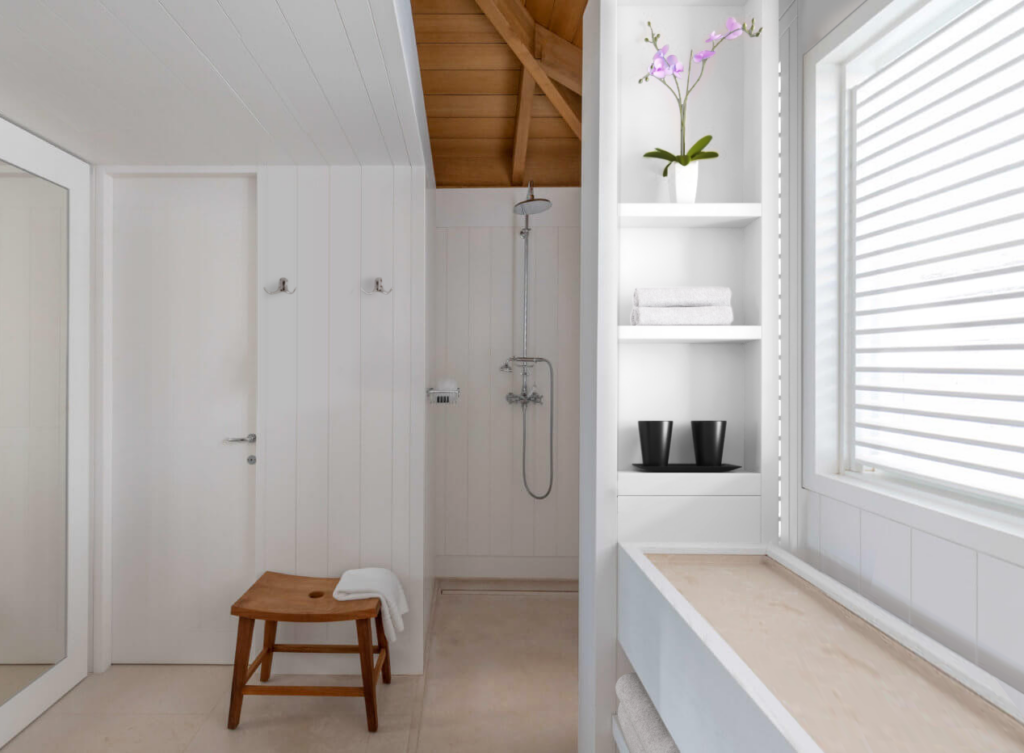 Bathroom and dressing space at Le Sereno Hotel in St. Barthélemy with white wood panelling, open shower and minimalist tropical design.